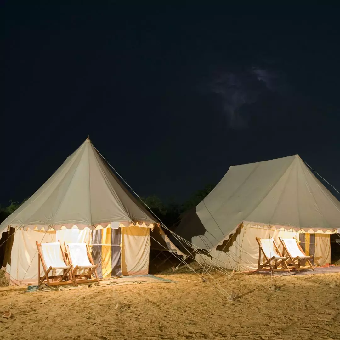 Förtält på strand med solstolar matta lampa och handdukar ser mysigt ut på kvällen och mörkret.
