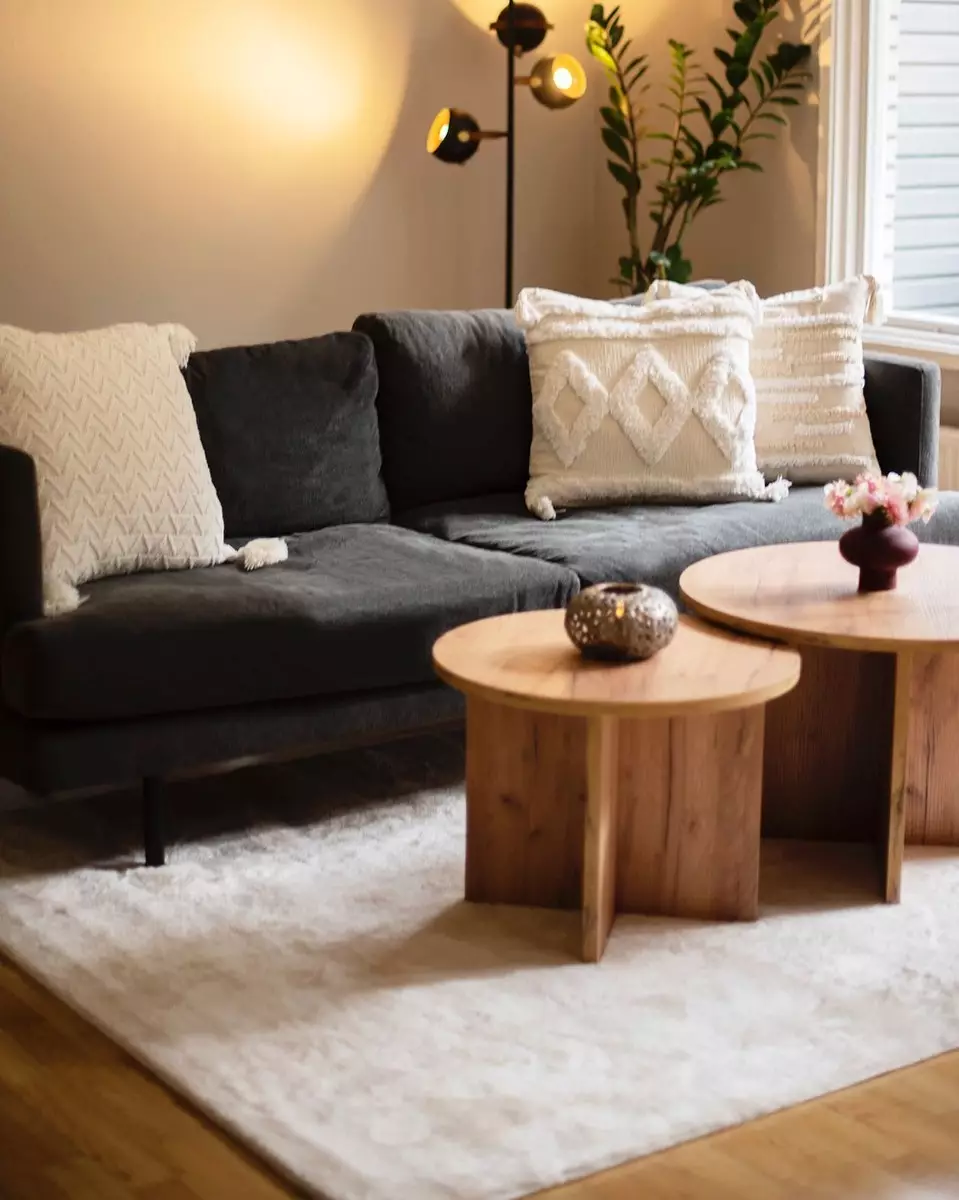 Runt träbord med beige matta under i vardagsrummet.
