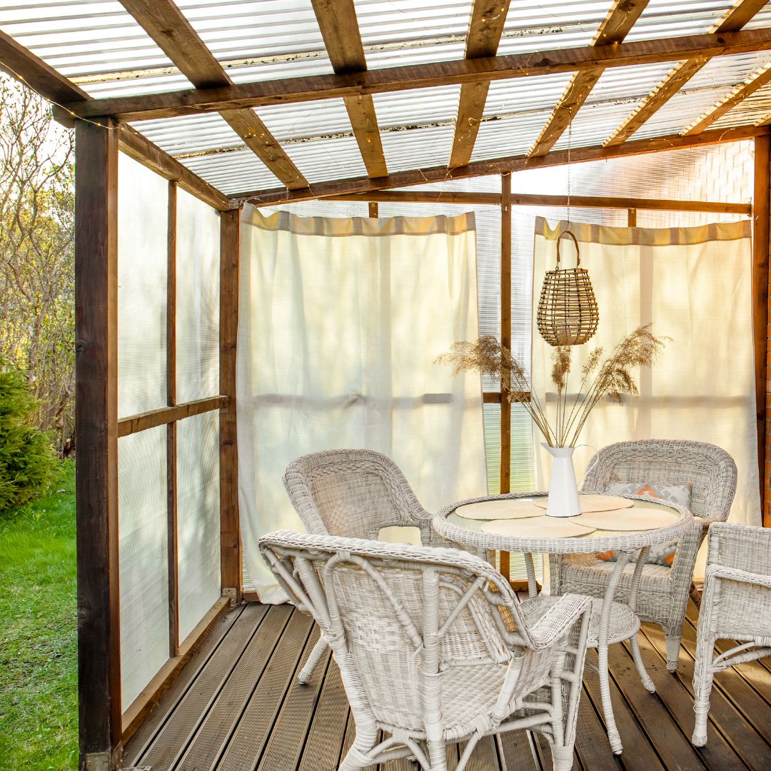 En altan med gardiner som hänger fint för att skydda mot stark sol och varmt väder.