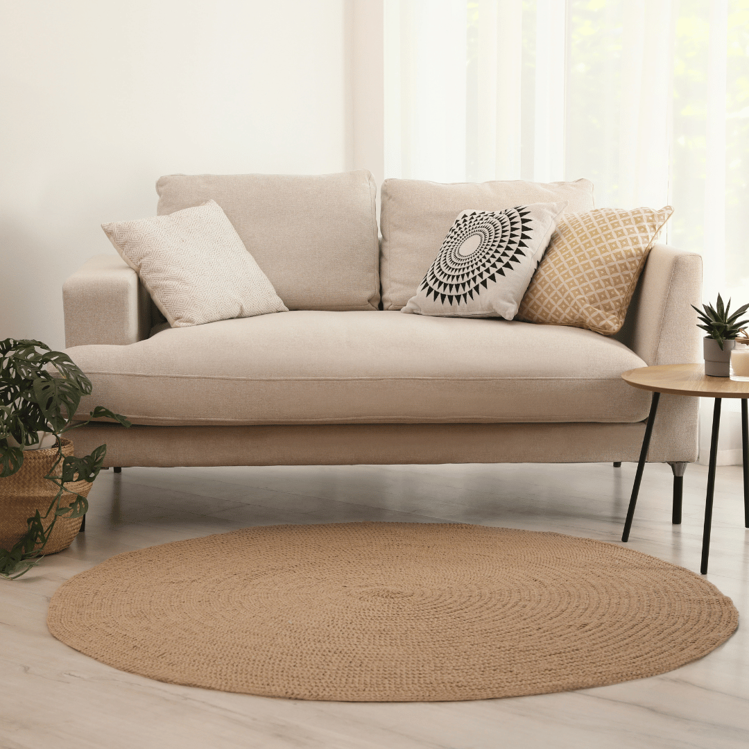 En rund sisalmatta i ett vardagsrum med bohemisk stil. Mattan är placerad framför en krämfärgad soffa och ser väldigt bra ut.