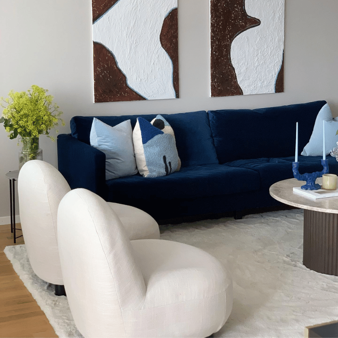 En vit halkmatta med gummibaksida som förebygger halka. Den är placerad under en blå soffa och två vita fåtöljer i ett snyggt vardagsrum.