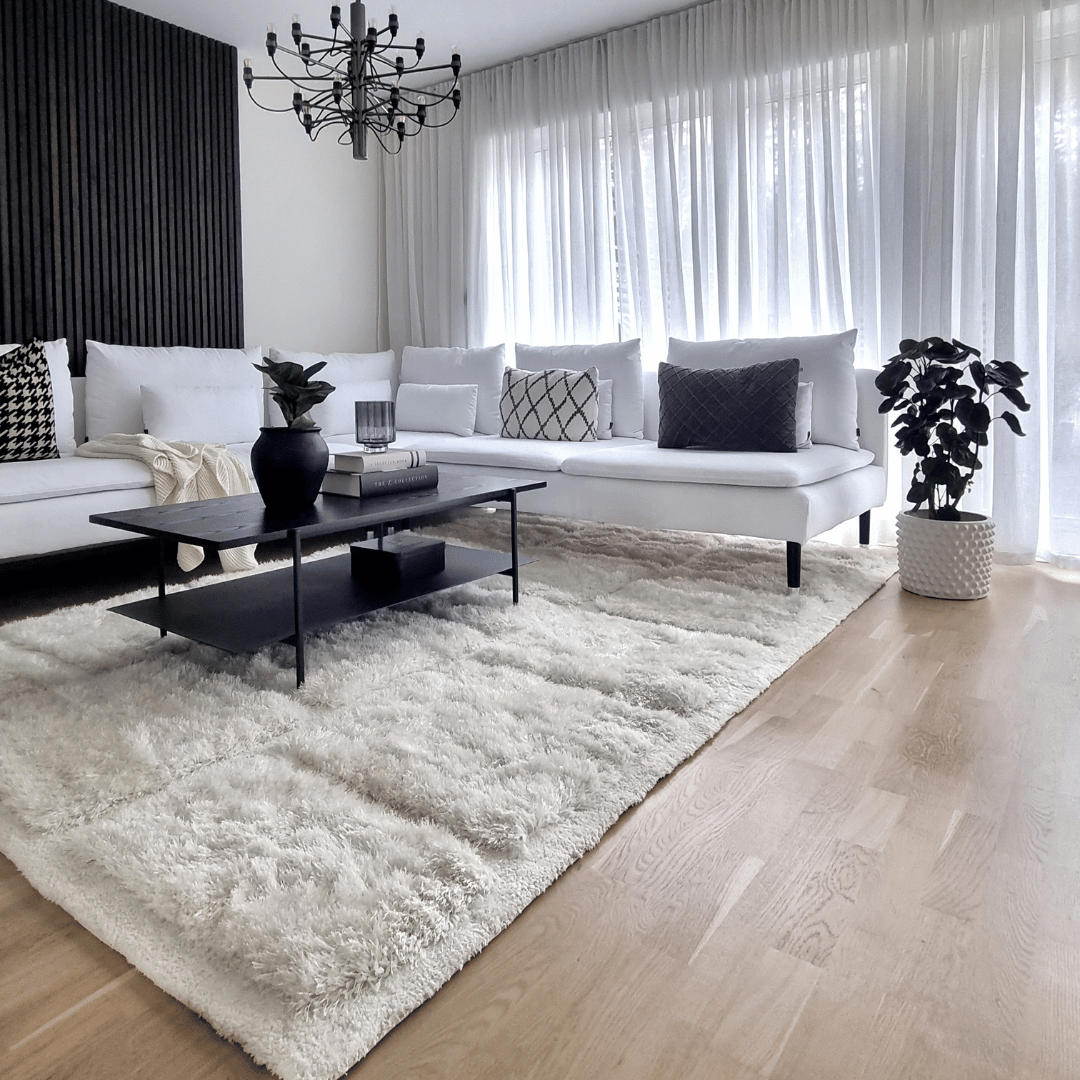 Maskinvävd matta i vardagsrum med stor soffa och soffbord på mattan.