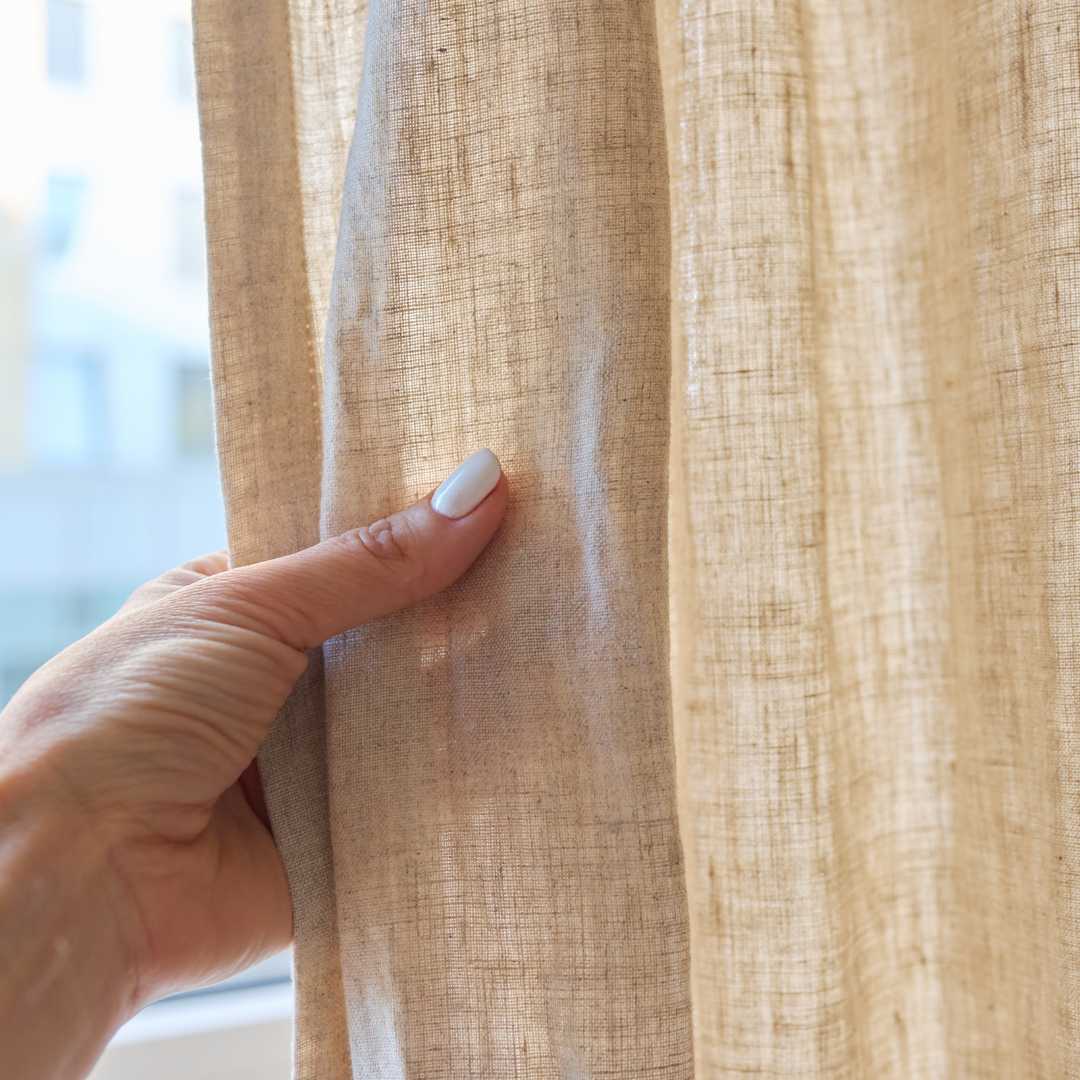 Person känner på gardiner med hand för att hitta ettiket och tvättråd.