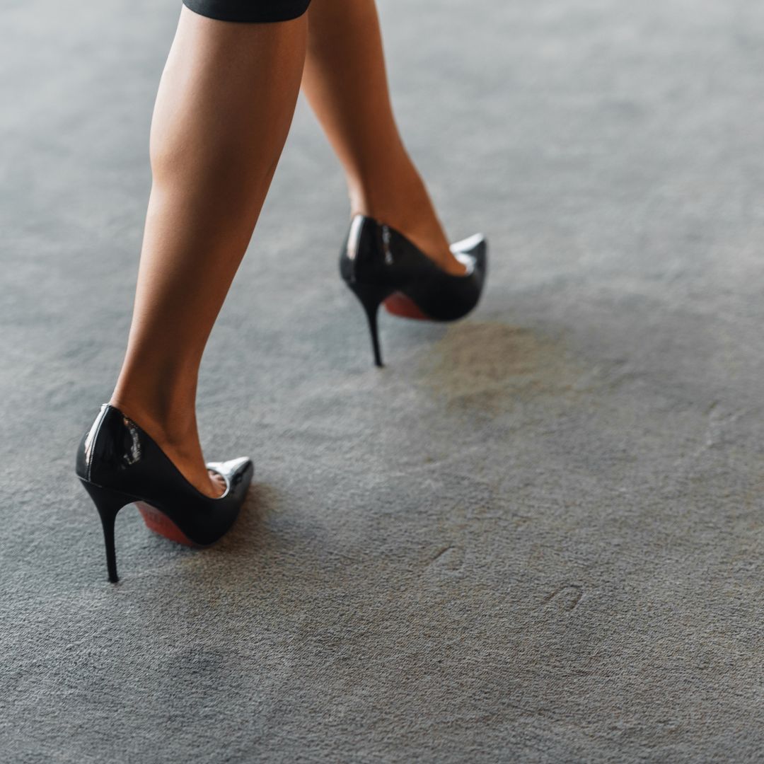 Kvinna med högklackade skor går på en varm matta i kontoret.