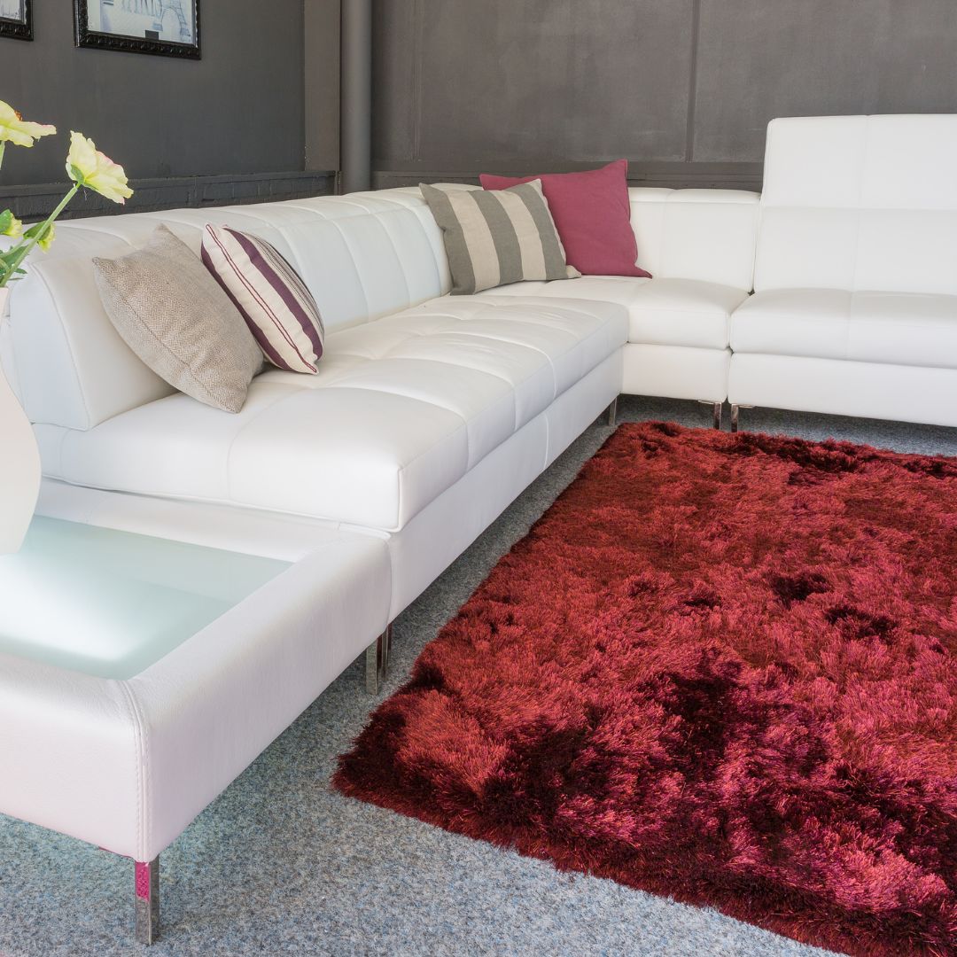 Röd matta till vit soffa i stort vardagsrum i modern inredningsstil.