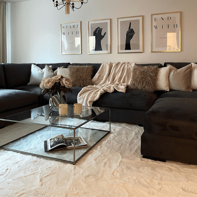 Mörk soffa med ljus matta under som skapar kontrast och en välkomnande inredning.