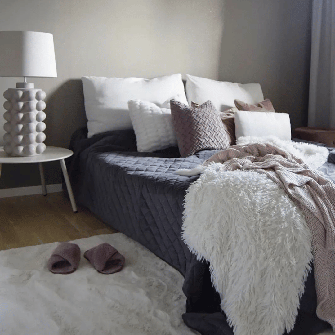 Ett mysigt sovrum med mjuk matta i vit färg samt blå färgpalett på säng och dekorationer.