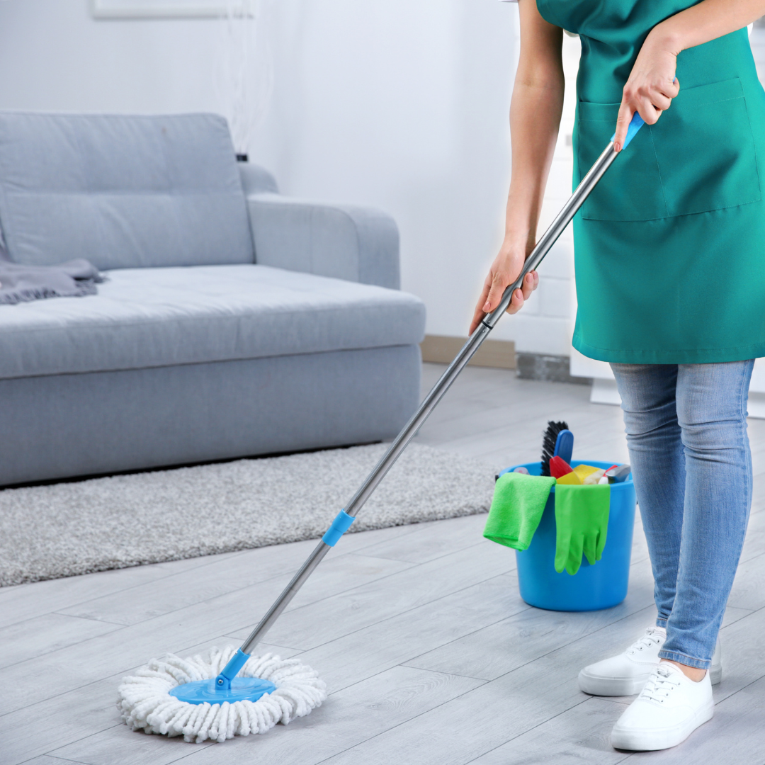 Kvinna moppar och städar vardagsrummet i sitt hem.